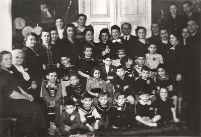Tallinn - 1940 - Fanny Dubovski Jewish Kindergarten
Left to right.
At the top right corner: Tsila Manoim, Hasin
Parents: Rocha Zimbalov, ?, ?, Rosa Piel, Rocha Klutschik, Umov, Sara Blum, ?, Sonja Beilinson, ?, ?,  Efraim Rochlin,  Hena Aronovitsch, Dr Ring, ?, Fanni Dubovski, Goldmann, ?
Children:
Sitting on the floor: ?, Isak Beilinson, Gabi Piel, Nata Ring, Buba Goldmann, Lia Goldmann
Sitting on the chairs: Gabi Manoim, ?, Ranja Manoim (Blum), ?, Benno Haitin, ?
Standing: Faivi Klutschik, Ruti Ring, Lia Rogovski, Wulf Umov, Lia Zaks, Schloma Aronovitsch, Abi Hasin, Slomka 
