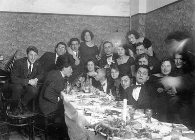 Company
Left to right.
At the table: ?, Anna Levin (Rogovski), Nosson Gens, Raja Drabkin (Feinstein), ?, Mischa Bakscht
Standing: Leo Markovitsch, ?, Dobruschkes?, ?, Samuil Levin,  Anna Feinstein, ?, ?,  ?, Margarete (Grete) Elian
